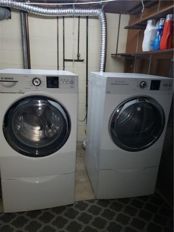 laundry area featuring concrete block wall and separate washer and dryer