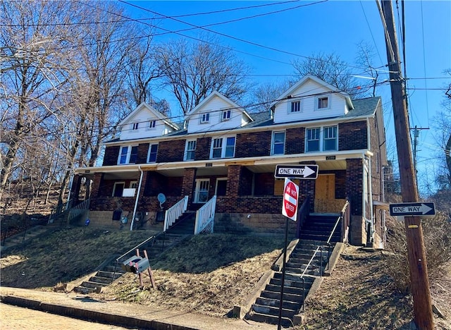 view of front of home featuring stairs, a porch, and brick siding