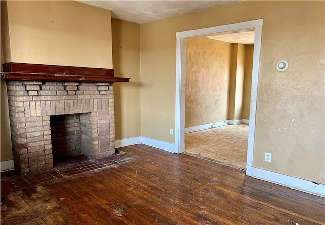 unfurnished living room with hardwood / wood-style flooring, a fireplace, and baseboards