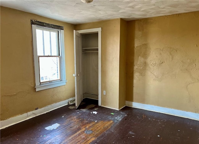 unfurnished bedroom featuring a closet, baseboards, and hardwood / wood-style flooring