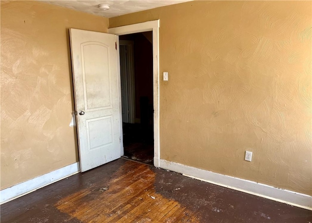 empty room featuring baseboards and hardwood / wood-style flooring