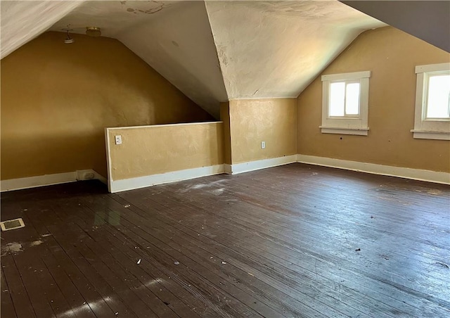 additional living space featuring vaulted ceiling, dark wood-style floors, and visible vents