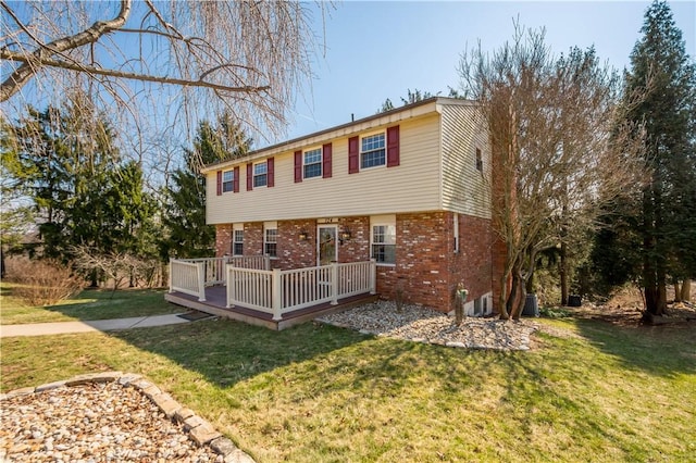 view of front facade with a front yard, brick siding, central AC, and a wooden deck