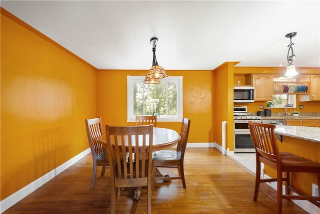 dining space with baseboards and light wood-style flooring