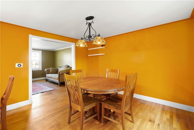 dining room featuring crown molding, baseboards, and light wood finished floors