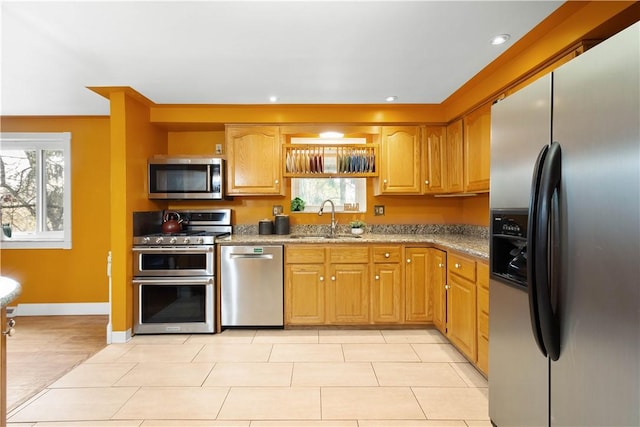 kitchen with light stone countertops, baseboards, recessed lighting, a sink, and stainless steel appliances