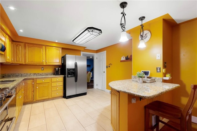 kitchen with light stone counters, a breakfast bar, hanging light fixtures, appliances with stainless steel finishes, and brown cabinets