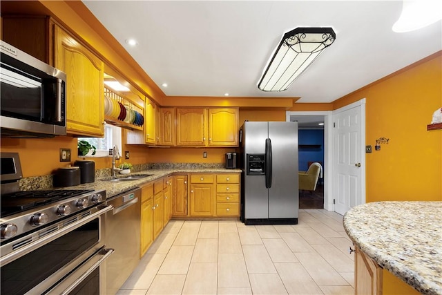 kitchen featuring brown cabinets, a sink, recessed lighting, appliances with stainless steel finishes, and light stone countertops