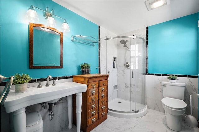 bathroom with tile walls, marble finish floor, toilet, and a shower stall