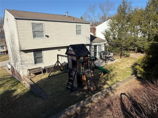 rear view of property featuring a playground, a yard, and a patio area