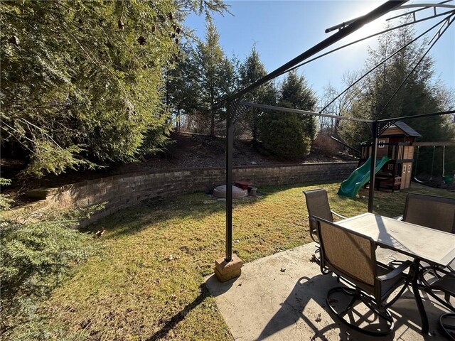 view of yard with a patio area, outdoor dining space, and a playground