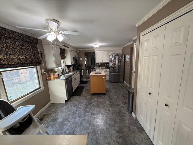 kitchen with ornamental molding, a sink, a kitchen island, freestanding refrigerator, and baseboards