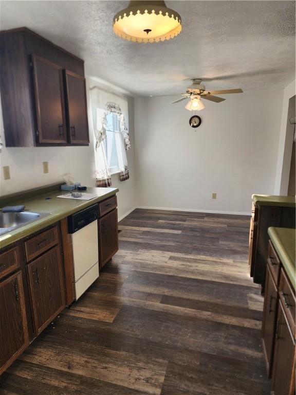 kitchen with a sink, a textured ceiling, dishwasher, and dark wood finished floors