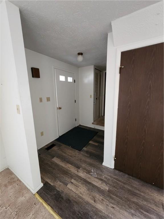 foyer entrance featuring visible vents, wood finished floors, baseboards, and a textured ceiling