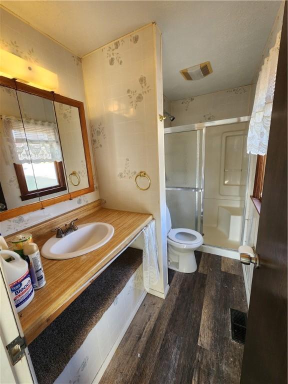 full bathroom featuring visible vents, a stall shower, toilet, and wood finished floors