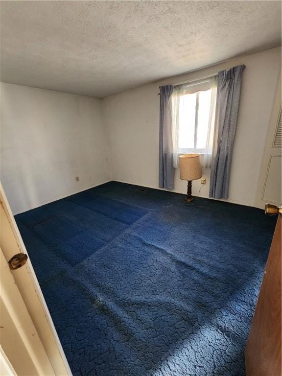 empty room with carpet floors and a textured ceiling