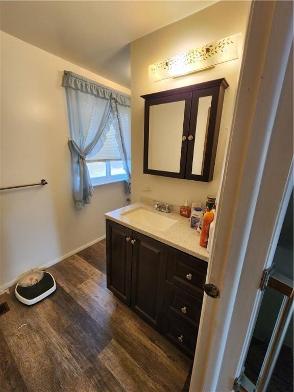 bathroom with baseboards, wood finished floors, and vanity