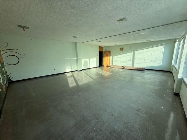 spare room featuring tile patterned floors, a textured ceiling, and concrete block wall