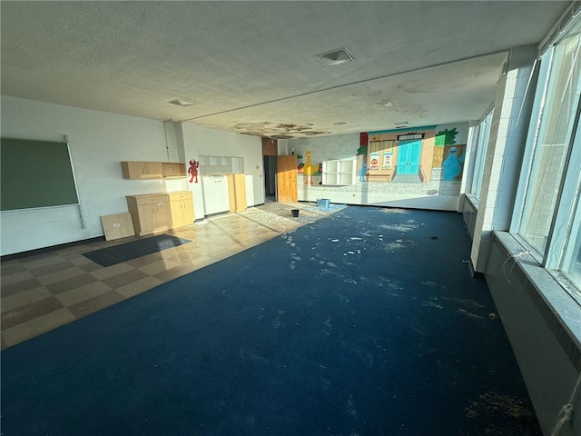 interior space featuring tile patterned floors, a textured ceiling, and concrete block wall