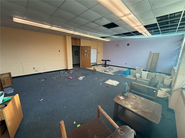 interior space with a drop ceiling and concrete block wall