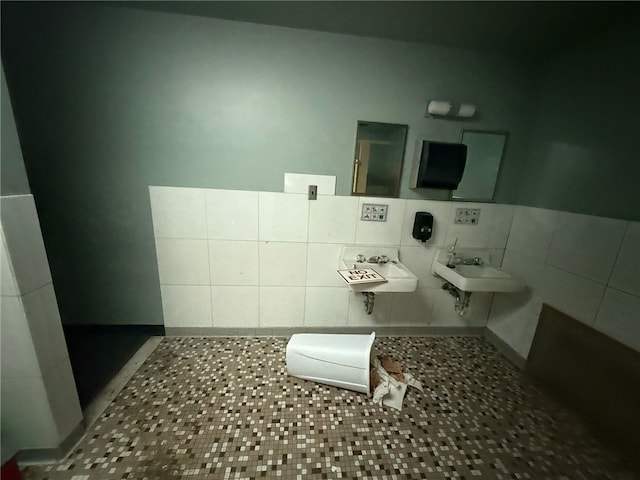 half bathroom with tile patterned flooring, tile walls, and a sink