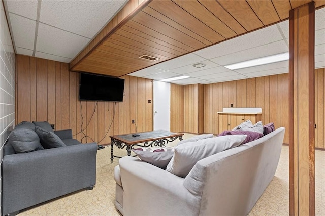 living room with visible vents, a paneled ceiling, light floors, and wood walls