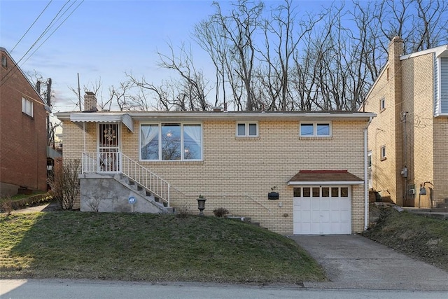 view of front of house featuring a front yard, driveway, a chimney, a garage, and brick siding