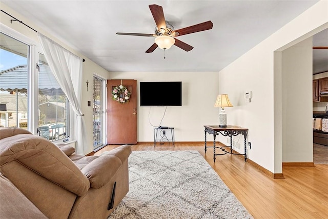 living room with light wood-type flooring, baseboards, and ceiling fan