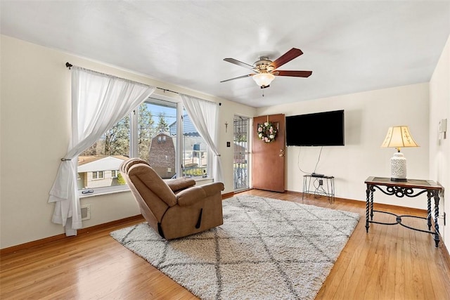 living room with baseboards, a ceiling fan, and wood finished floors