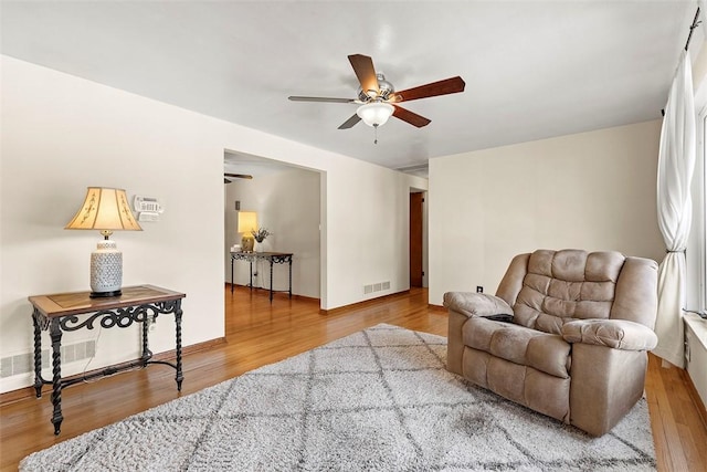 living room with visible vents, baseboards, a ceiling fan, and wood finished floors