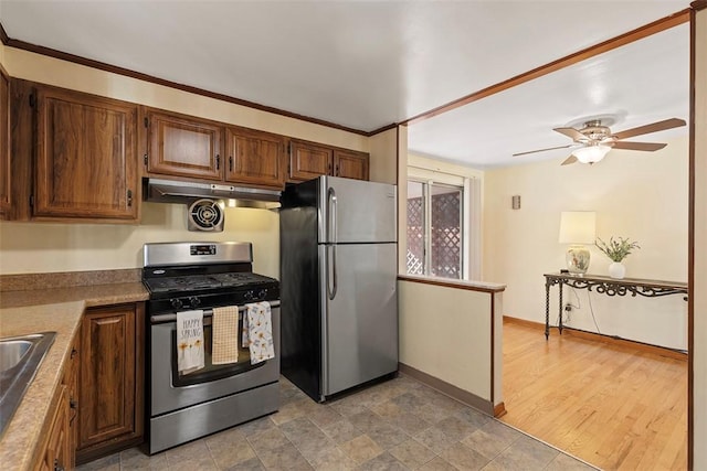 kitchen featuring a sink, under cabinet range hood, appliances with stainless steel finishes, baseboards, and ceiling fan