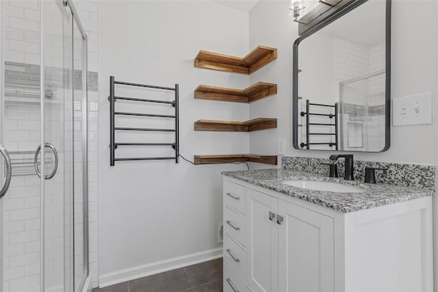 bathroom featuring vanity, a shower stall, baseboards, and tile patterned floors