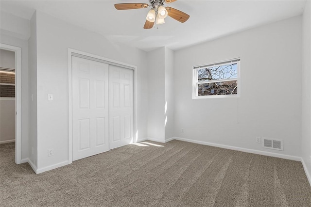 unfurnished bedroom featuring carpet, visible vents, a closet, and baseboards