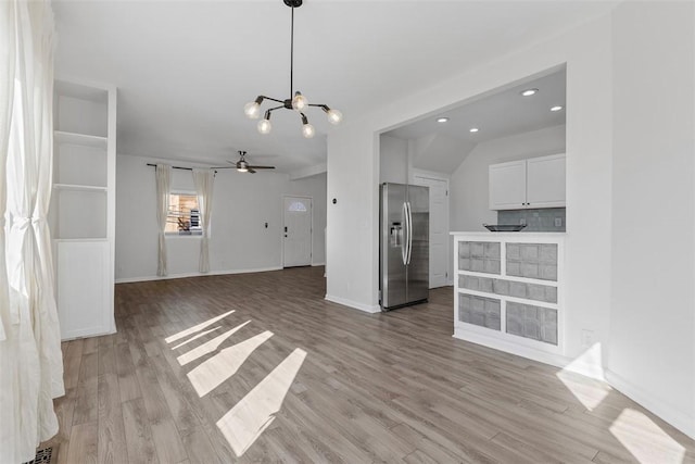 unfurnished living room with light wood-type flooring, lofted ceiling, baseboards, and ceiling fan