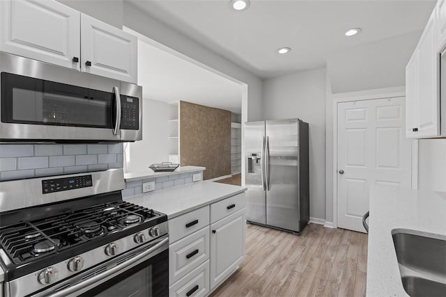 kitchen featuring light wood-type flooring, tasteful backsplash, white cabinetry, recessed lighting, and appliances with stainless steel finishes