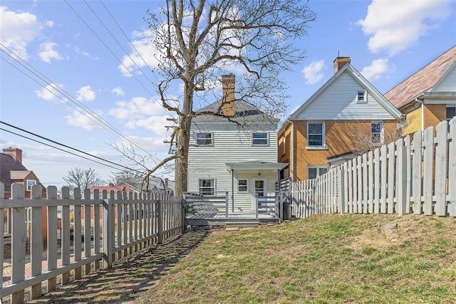 back of property featuring brick siding, a lawn, a wooden deck, and a fenced backyard