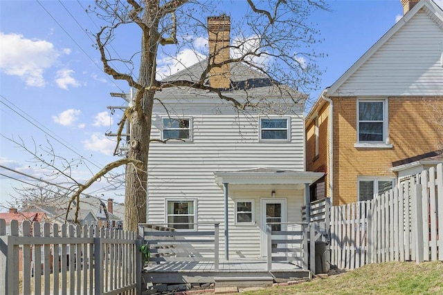 back of house featuring a chimney and fence