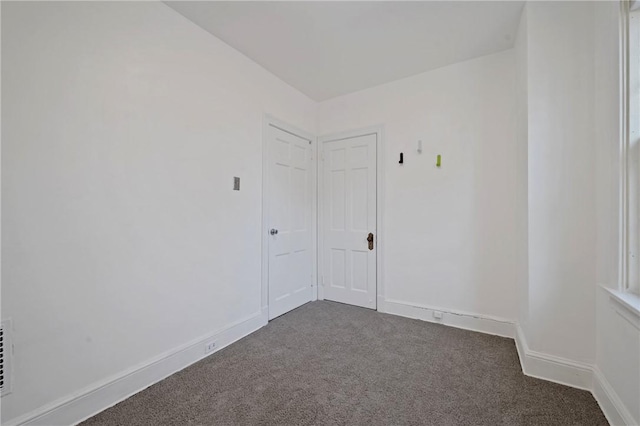 empty room featuring dark carpet and baseboards