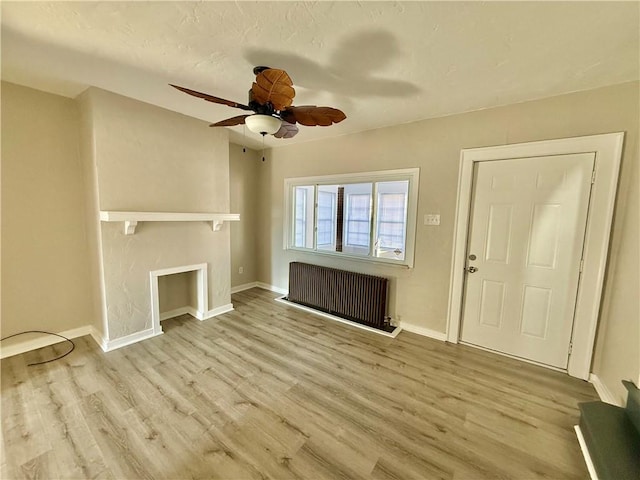 unfurnished living room featuring ceiling fan, radiator, baseboards, and wood finished floors