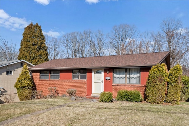 ranch-style home featuring brick siding, a front lawn, and a shingled roof