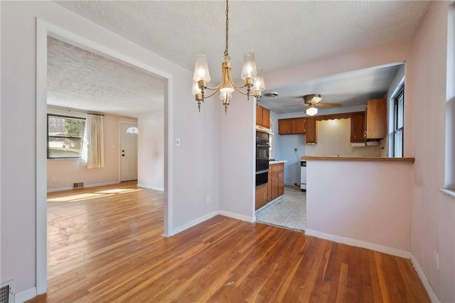 kitchen featuring light wood-style flooring, brown cabinetry, visible vents, and baseboards