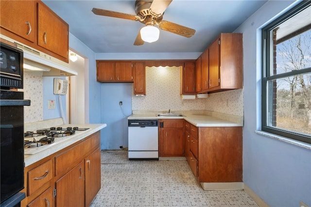 kitchen featuring white appliances, light floors, a sink, light countertops, and brown cabinets