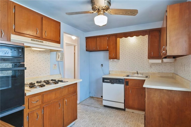 kitchen with white appliances, brown cabinetry, under cabinet range hood, and a sink