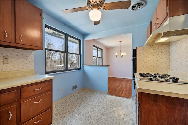 kitchen with tasteful backsplash, visible vents, baseboards, under cabinet range hood, and light countertops