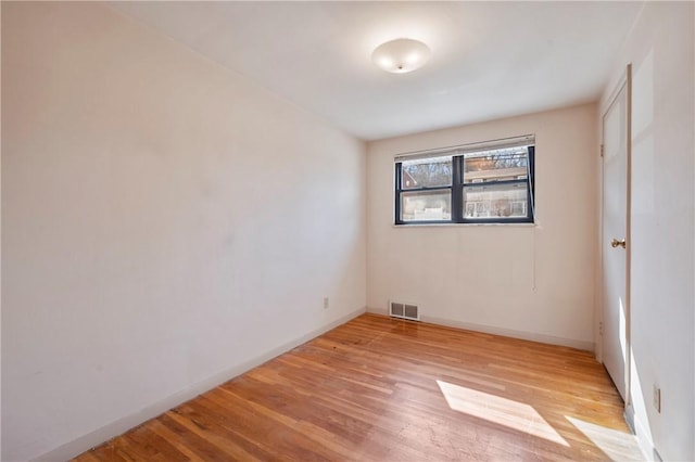 unfurnished room with visible vents, light wood-style flooring, and baseboards