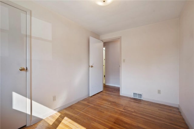 unfurnished bedroom with visible vents, baseboards, and wood finished floors