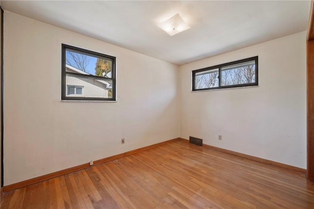 spare room with visible vents, baseboards, and light wood finished floors