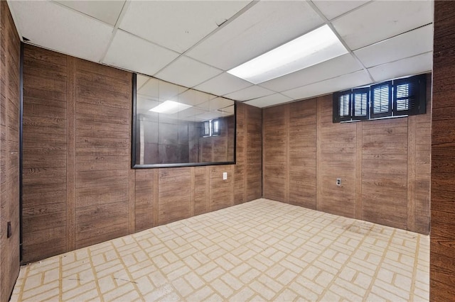 finished basement with a drop ceiling and wood walls