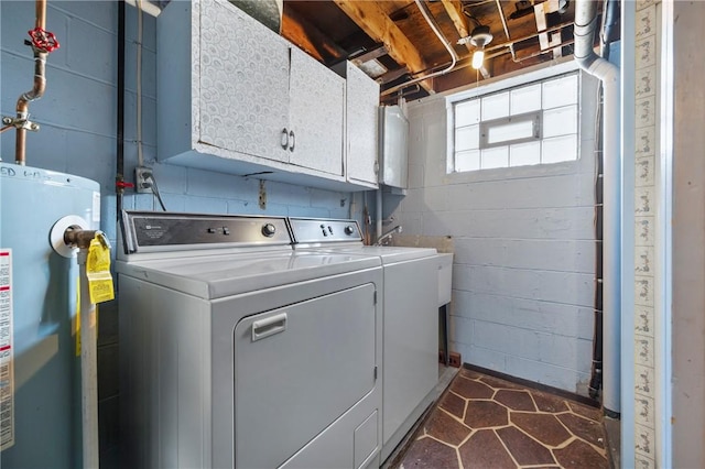 laundry room featuring cabinet space, concrete block wall, washing machine and dryer, and water heater