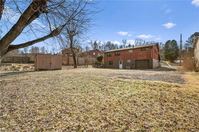 view of yard with fence, central AC unit, a garage, an outbuilding, and a storage unit